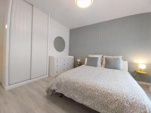 a white bedroom with a bed and a dresser at Élégance et charme aux portes de Paris in Saint-Ouen