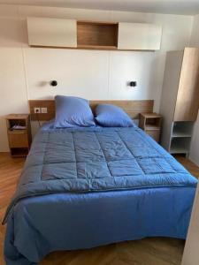 a blue bed with blue pillows in a bedroom at Chez Maya 2 chambres dont suite parentale et 2 salles de bain dans camping 4 étoiles in Saint-Julien-en-Born