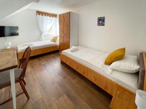 two beds in a room with a table and a desk at Tanyacsárda Panzió in Baja
