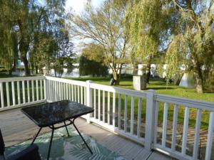 Una silla negra colocada en una terraza junto a una valla. en Delightful Caravan With A Lake View At Southview Holiday Park Ref 33026Cl, en Winthorpe