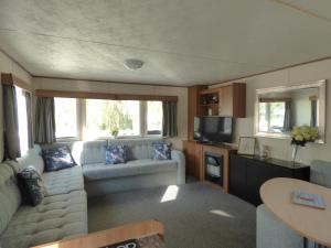 Una sala de estar con un sofá y un televisor. en Delightful Caravan With A Lake View At Southview Holiday Park Ref 33026Cl, en Winthorpe