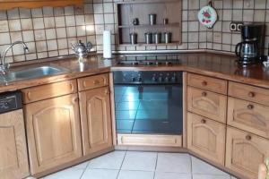 a kitchen with wooden cabinets and a stove and a sink at NEU! Ferienwohnung Ebbe in Utarp