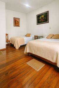 two beds in a room with wooden floors at HOTEL EL SOL dEL GALERAS in Pasto