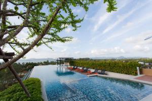 an infinity pool with chairs and a view from a house at 6th Avenue Surin Beach - Official Account in Surin Beach