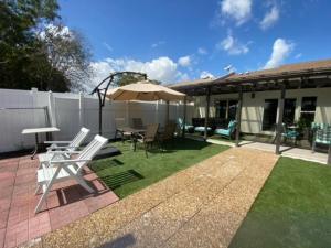 a patio with a table and chairs and an umbrella at Newly Renovated Villa with Hot Tub in Fort Lauderdale