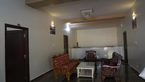 a living room with two chairs and a table at Chirooss Homestays And Resorts in Chikmagalūr
