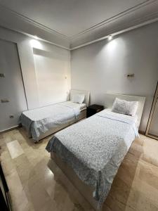 two beds in a room with white walls at Corniche Casablanca in Casablanca
