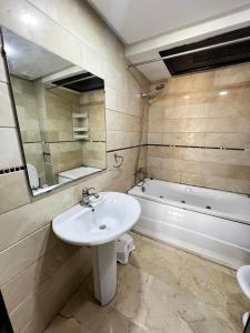 a bathroom with a sink and a mirror and a tub at Corniche Casablanca in Casablanca