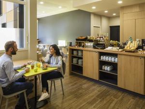 a man and woman sitting at a table in a restaurant at Aparthotel Adagio access Montpellier Centre in Montpellier