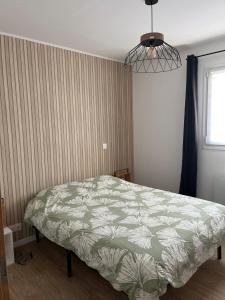 a bedroom with a bed with a green and white comforter at L'instant fleuri in Saint-Hippolyte