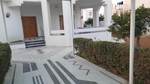 a white building with a door and a sidewalk at Azur villa in Sfax