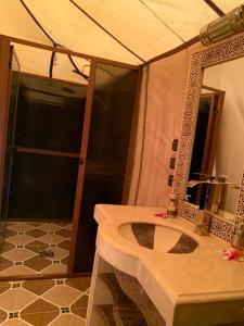 Un baño con ducha y lavabo con espejo. en Luxury white camp, en Merzouga