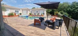 Un patio con una mesa y sillas y una sombrilla. en Villa Monplaisir, en Montolieu