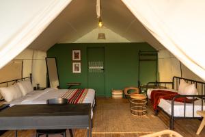 a bedroom with two beds and a green wall at Husaak Tabab Adventure Lodge 
