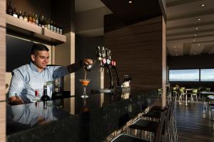 a man is making a drink at a bar at Hampton By Hilton Bogota Airport in Bogotá +36 photos