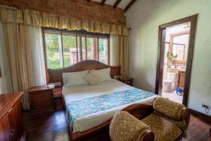 a bedroom with a bed and a chair and a window at Finca Hotel Villa Camila in Copacabana
