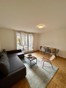 een woonkamer met een zwarte bank en een tafel bij Comfort escape on Schwandenwiesen in Zürich +24 foto's