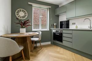 a kitchen with green cabinets and a table and chairs at Pippin - Stylish City Centre Studio - Worcester in Worcester