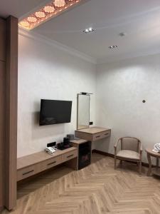 a living room with a tv and a table and a chair at Oldtown1111 in Samarkand
