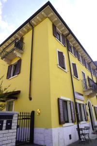 a yellow building with black windows and a fence at OverGarden Rooms in Dossobuono