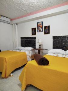 2 camas en una habitación con sábanas amarillas en Hotel El Almendro, en Pedernales