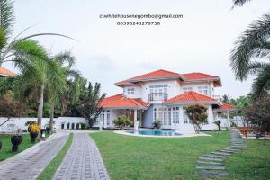a house with a swimming pool and palm trees at Cs white house negombo in Negombo