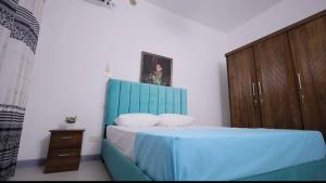 a bedroom with a blue bed and a wooden cabinet at Cs white house negombo in Negombo