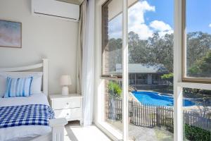 a bedroom with a bed and a view of a pool at Peaceful Bushland Retreat with Treetop Hills Views in Wonga Park