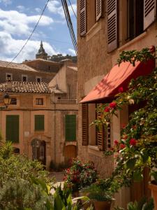Un edificio antiguo con un toldo rojo y flores. en Marton Valldemossa Turismo de Interior, en Valldemossa