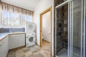 a bathroom with a washing machine and a shower at Tranquil Cottage with Valley and Hills Views in Wonga Park