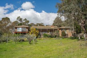 a house in the middle of a field at Country Charm Cottage with Pool and Forest Views in Wonga Park