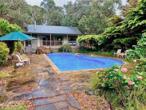 a swimming pool in front of a house at Country Charm Cottage with Pool and Forest Views in Wonga Park +24 photos