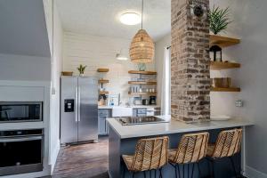 a kitchen with a counter with chairs and a refrigerator at Historic and charming duplex in desirable midtown, close to the beach and strand in Galveston