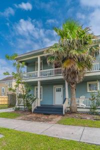 a house with a palm tree in front of it at Historic and charming duplex in desirable midtown, close to the beach and strand in Galveston