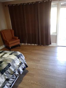 a bedroom with a bed and a chair and a window at Sherwood Inn Motel in Brantford