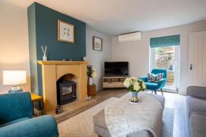 a living room with a fireplace and blue chairs at Old Orchard Cottage in Moreton in Marsh +17 photos