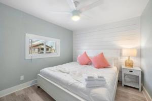a bedroom with a bed with pink pillows and a window at Cozy beach bungalow close to ocean with large yard in Galveston +42 photos