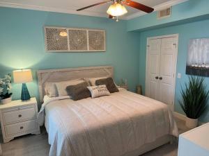 a bedroom with a bed with blue walls and a ceiling fan at Modern condo right across from beach and pool in Galveston +41 photos