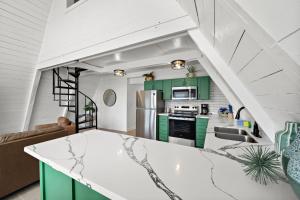 a kitchen with green cabinets and a white counter top at Cozy A-frame with Fenced Yard, Fire Pit, Gulf View in Surfside Beach