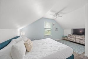 a bedroom with a white bed and a ceiling fan at Bright and Cozy 4 Bedroom close to the Ocean in Galveston