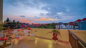 a balcony with chairs and potted plants and a sunset at Villa Griya Anyar Ubud in Ubud