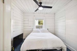 ein Bett in einem weißen Zimmer mit einem Deckenventilator in der Unterkunft Historic Galveston homes, close to all the island has to offer in Galveston