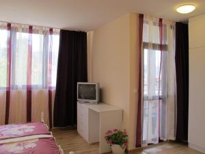 1 dormitorio con cama y vestidor con TV en Guest House & Bistro Lefterova en Kotel