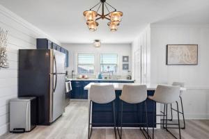 Una cocina con refrigerador y una encimera con taburetes. en Cute beach house with large deck and fire pit, close to the beach, en Galveston