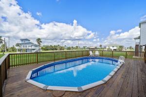 una piscina en una terraza de madera junto a una valla en Cute beach house with large deck and fire pit, close to the beach, en Galveston