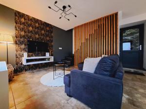 a living room with a blue couch and a tv at Gîte Chez Nénene La Roche en Ardenne in La Roche-en-Ardenne