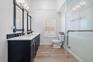 un bagno con due lavandini, una doccia e un WC di Modern Downtown Galveston Loft, Walk to The Strand a Galveston Altre 27 foto