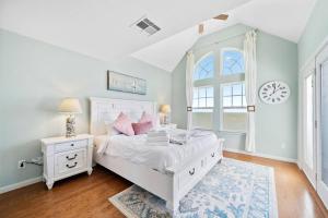 Stunning bayfront home with spacious deck and incredible Galveston Bay views في Shoreacres: غرفة نوم بسرير ابيض وساعة على الحائط