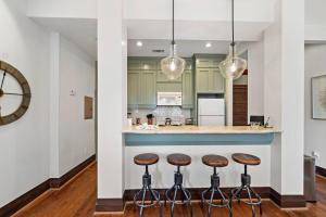 Historic loft in downtown Galveston close to everything في جالفيستون: مطبخ مع خزائن خضراء وكراسي البار +23 صورة