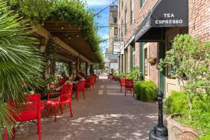 Historic loft in downtown Galveston close to everything في جالفيستون: فناء مع كراسي حمراء وأشخاص يجلسون في مطعم